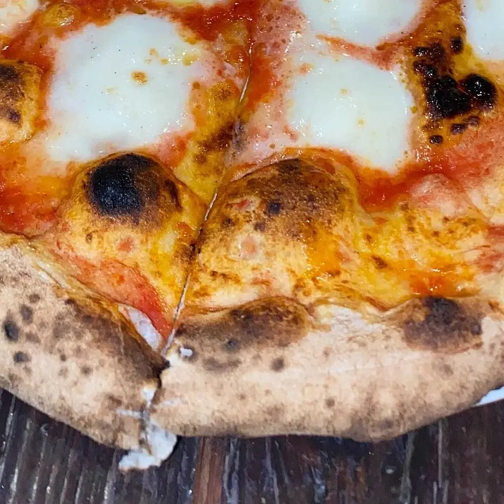 Zbliżenie na przypieczony, wyrośnięty rant pizzy z mozzarellą